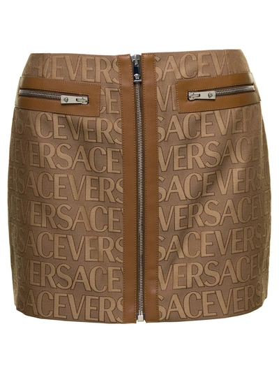 VERSACE BROWN MINI -SKIRT WITH ALL-OVER LOGO LETTERING PRINT IN CANVAS WOMAN