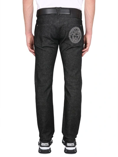 Versace Logo Embellished Straight Leg Jeans In Black