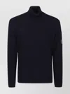 C.p. Company Ribbed Knit Roll Neck Sweater With Signature Lens Detail And Zip Pocket In Black