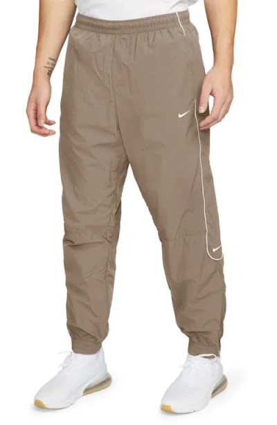 Nike Solo Swoosh Water Repellent Track Pants In Khaki/white