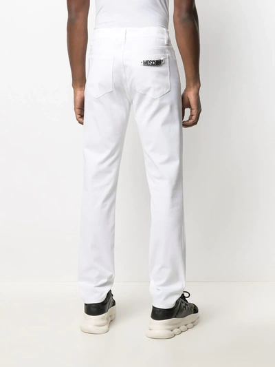 Shop Moschino Logo Plaque Denim Jeans In White