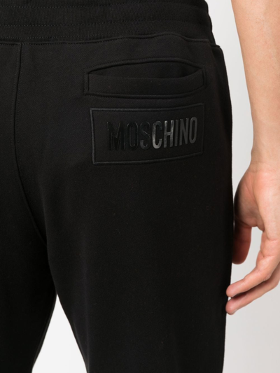 Shop Moschino Embossed-logo Cotton Trousers In Schwarz
