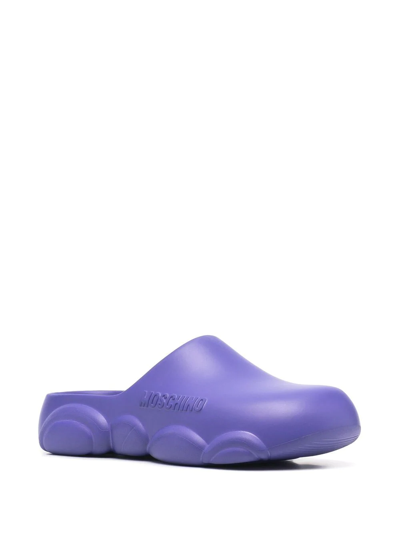 Shop Moschino Logo Embossed Mules In Purple