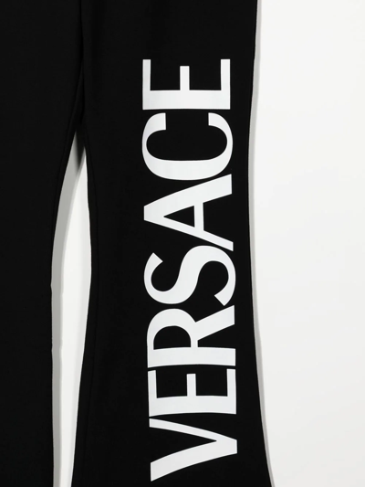 Shop Versace Logo-print Cotton Flared Trousers In Black