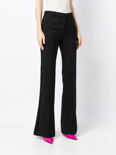 Shop Versace Flared Low-rise Trousers In Black