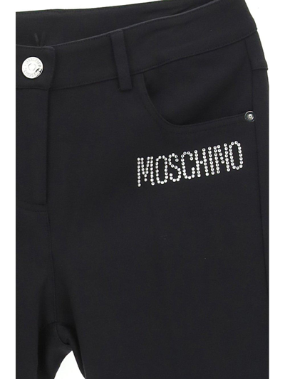 Shop Moschino Logo Embellished Straight Leg Pants In Nero
