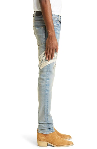 Shop Amiri Varsity Logo Distressed Stretch Denim Skinny Jeans In Clay Indigo