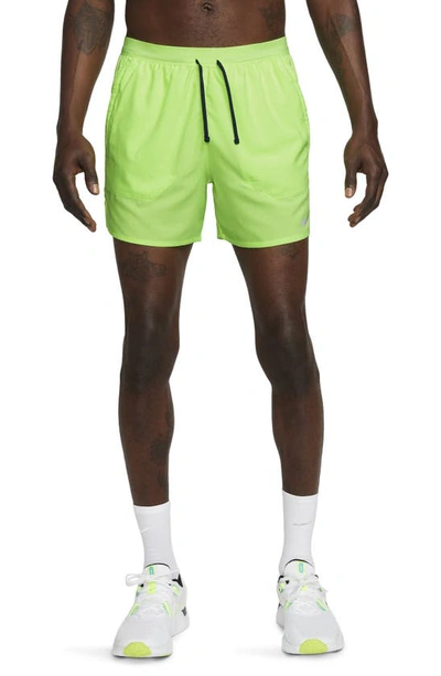 Shop Nike Dri-fit Stride 5-inch Running Shorts In Ghost Green/midnight Navy