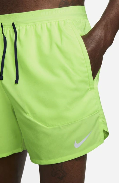 Shop Nike Dri-fit Stride 5-inch Running Shorts In Ghost Green/midnight Navy
