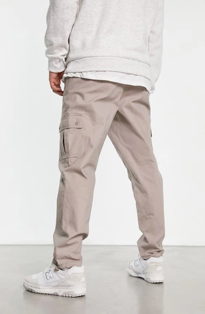 Shop Asos Design Tapered Cargo Trousers In Beige