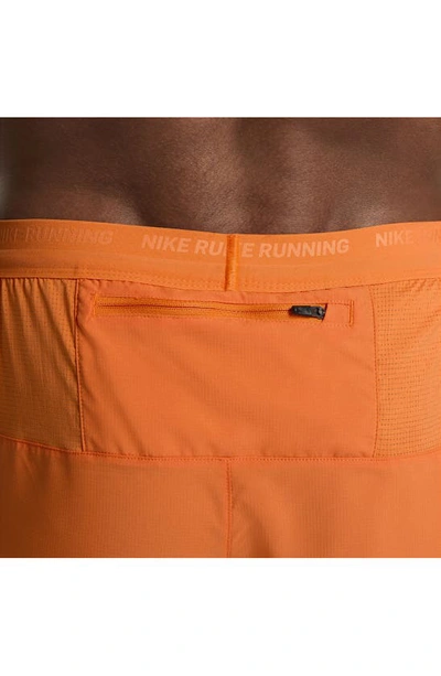 Shop Nike Dri-fit Stride 2-in-1 Running Shorts In Mandarin/ Dark Russet