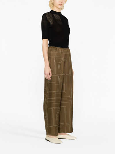 Shop Totême Monogram-print Silk Straight-leg Trousers In Green