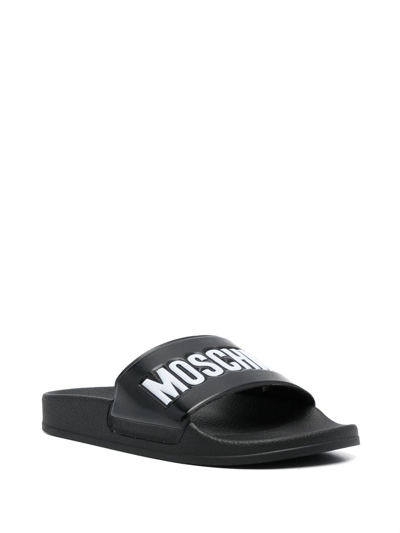 Shop Moschino Embossed-logo Flat Slides In Schwarz