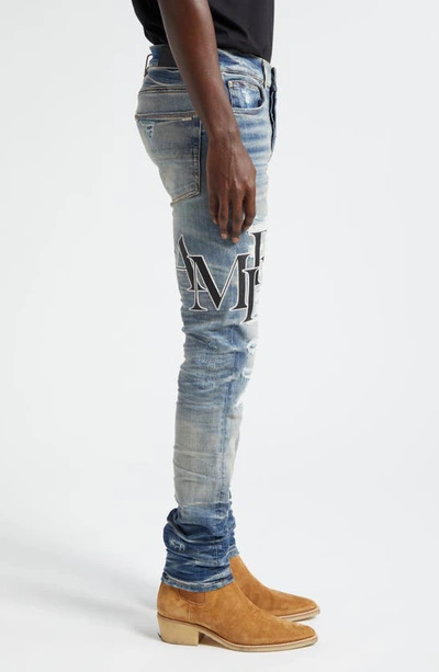 Shop Amiri Staggered Logo Distressed Skinny Jeans In Vintage Indigo