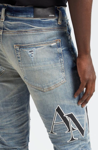 Shop Amiri Staggered Logo Distressed Skinny Jeans In Vintage Indigo