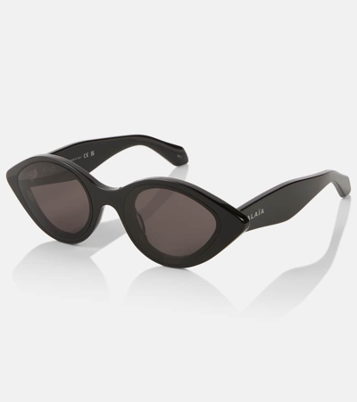Shop Alaïa Oval Sunglasses In Black