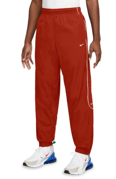 Shop Nike Solo Swoosh Water Repellent Track Pants In Dragon Red/ White