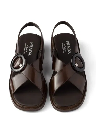 Prada Brushed Leather Crisscross Band Sandals With Plexiglas Buckle In Brown