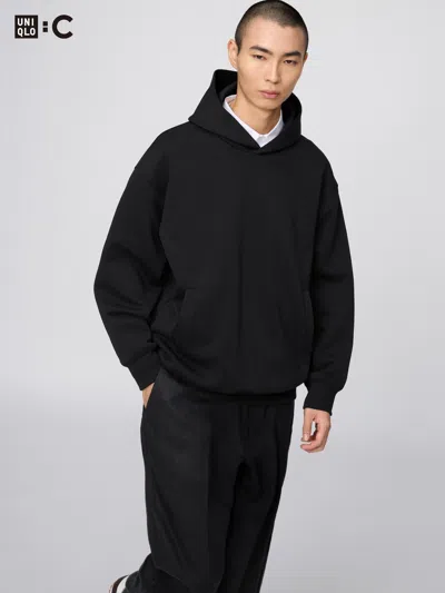 Black UNIQLO : C oversized pullover hoodie worn over a white shirt.