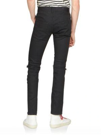 Shop Saint Laurent Ripped-knee Jeans In Black