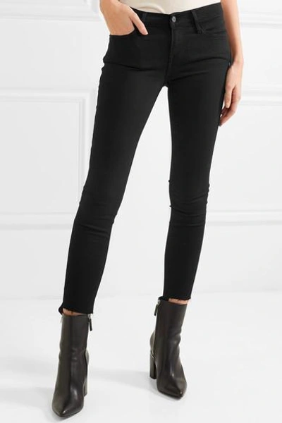 Shop Frame Skinny De Jeanne Raw Stagger Mid-rise Jeans