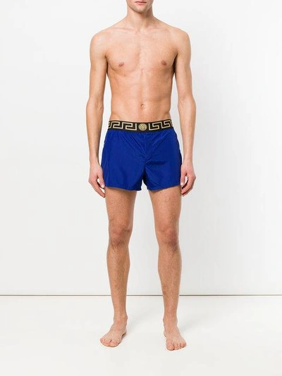 Shop Versace Grecca Waistband Swim Shorts In Blue