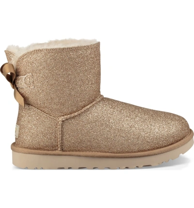Shop Ugg Mini Bailey Bow Sparkle Genuine Shearling Boot In Gold