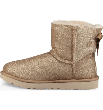 Shop Ugg Mini Bailey Bow Sparkle Genuine Shearling Boot In Gold