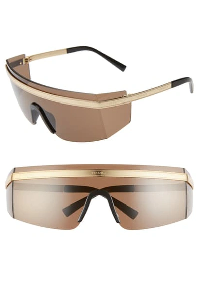 Shop Versace 65mm Shield Wrap Sunglasses - Gold/ Brown Solid