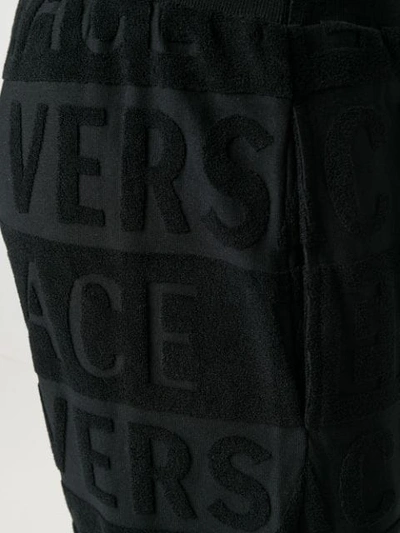 Shop Versace Textured Logo Track Pants In Black