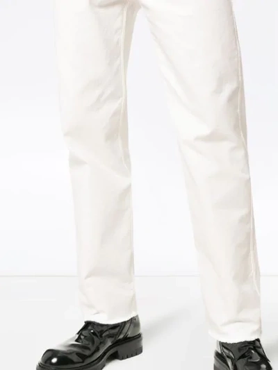 Shop Haider Ackermann Raw Hem Tapered Cotton Denim Jeans In White