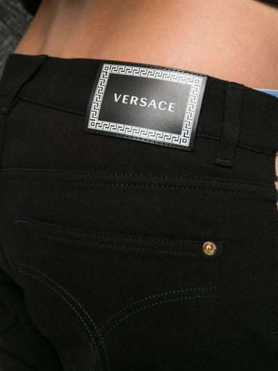 Shop Versace Leopard Print Panel Jeans In Black