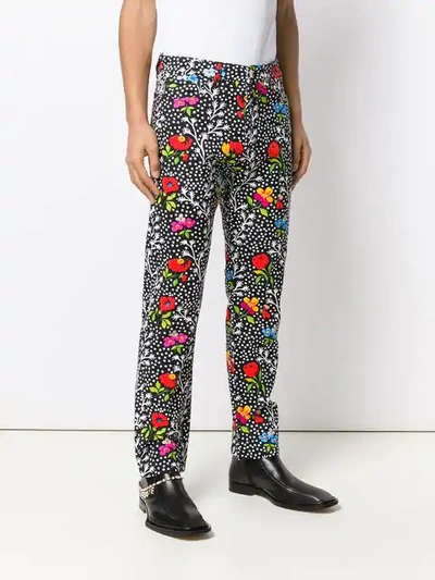 Shop Versace Floral Print Trousers In Black