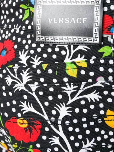 Shop Versace Floral Print Trousers In Black