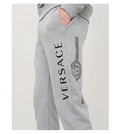 Shop Versace Logo-print Cotton-jersey Jogging Bottoms In Grigio Chiaro