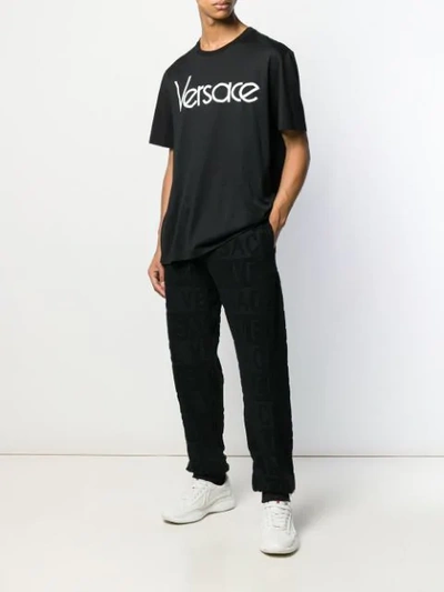 Shop Versace All Over Logo Track Trousers In Black