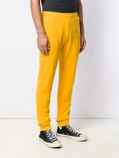 Shop Moschino Tonal Logo Print Track Pants In Yellow