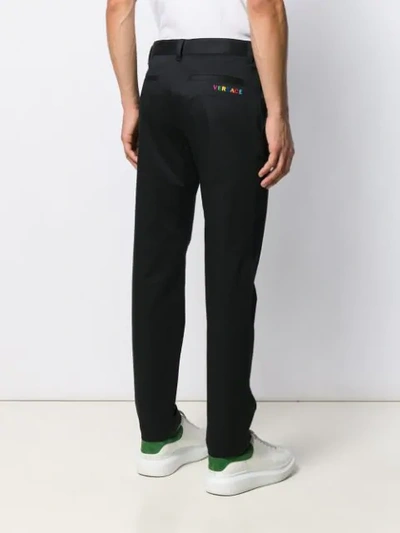 Shop Versace Embroidered Logo Chinos In Black