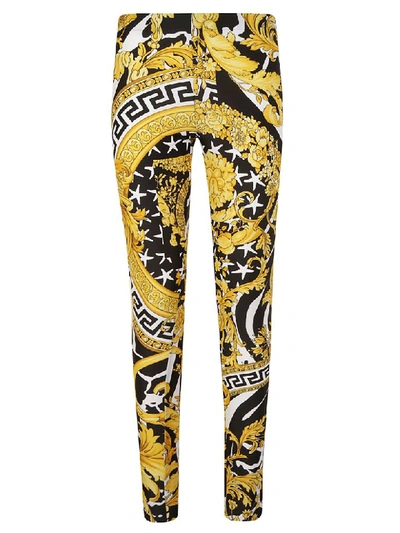 Shop Versace All-over Print Trousers In Black/gold