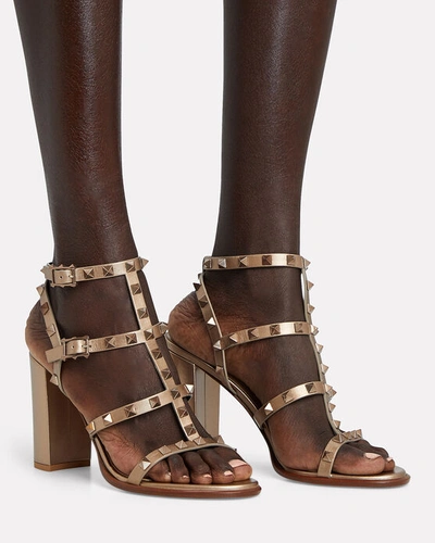 Shop Valentino Rockstud Gladiator Heeled Sandals In Gold