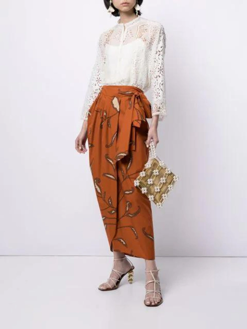 Farfetch's Post | Wearing: Biyan Sheer Lace Blouse In White; Johanna Ortiz Copper Eco Warrior Printed Cotton Wrap Skirt In Orange; Vanina Metallic Camelia Pearl Embellished Bracelet Bag In Neutrals