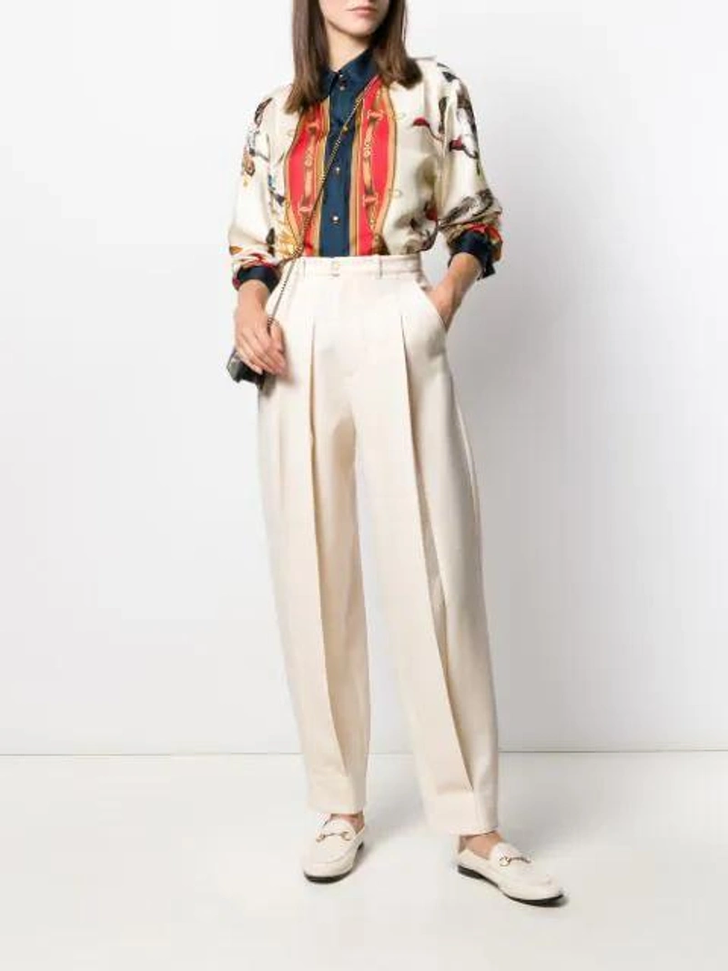 Farfetch's Post | Wearing: Gucci Brixton Horsebit-detailed Leather Collapsible-heel Loafers In White; Gucci Pleated Wool Trousers In Neutrals; Gucci Multicolor Women's Multicolored Bird Print Shirt In Neutrals