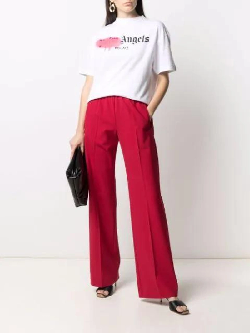 Farfetch's Post | Wearing: Palm Angels Bell Air Sprayed Cotton Jersey T-shirt In White; Off-white Spiral Panelled Tailored Trousers In Red; Kwaidan Editions Shopping Tote Bag In Black