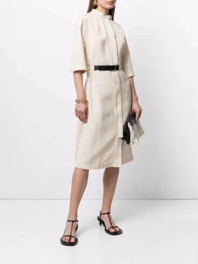 Farfetch's Post | Wearing: Jil Sander Belted Mock-neck Shirtdress In Neutrals; Jil Sander Black And White Two Tone Fold Over Leather Clutch Bag In Black/white; Jil Sander Gold Tone Fluid Folded Earrings