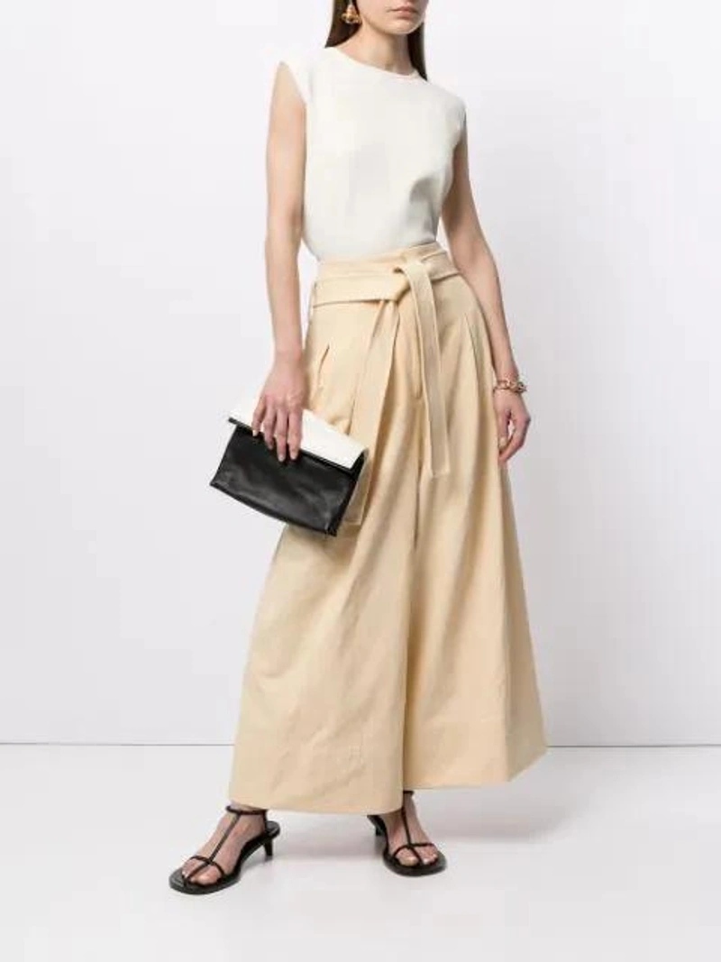 Farfetch's Post | Wearing: Jil Sander High-waisted Belted Palazzo Pants In Yellow; Jil Sander Round-neck Sleeveless Tank Top In White; Jil Sander Black And White Two Tone Fold Over Leather Clutch Bag In Black/white