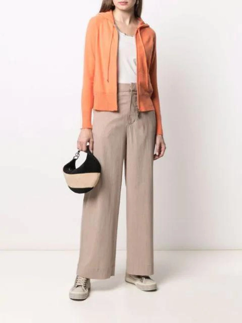 Farfetch's Post | Wearing: Chloé Chloe Pink And Grey Clint Trainers In Beige; Lorena Antoniazzi Knitted Zip-up Hoodie In Orange; Ganni High Rise Stretch Wide Leg Chino Trousers In Neutrals