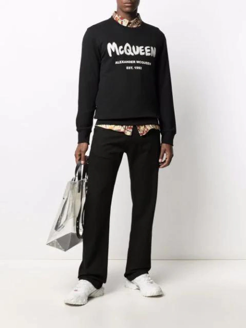 Farfetch's Post | Wearing: Alexander Mcqueen Logo-embroidered Straight-leg Jeans In Black; Martine Rose Paisley-print Long-sleeve Shirt In Red; Alexander Mcqueen Black & White Intarsia Logo Sweater