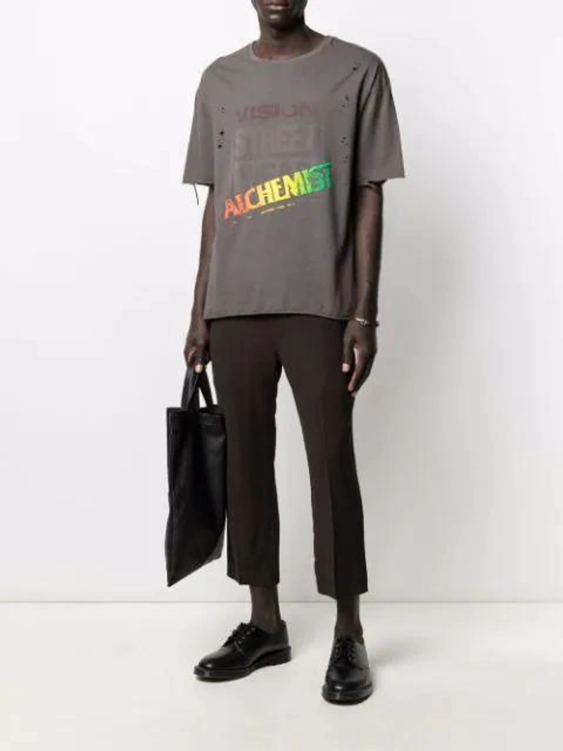Farfetch's Post | Wearing: Alchemist Distressed-effect Logo-print T-shirt In Black; Rick Owens Drawstring Trousers In Brown; Rick Owens Logo-embroidered Leather Tote Bag In Brown