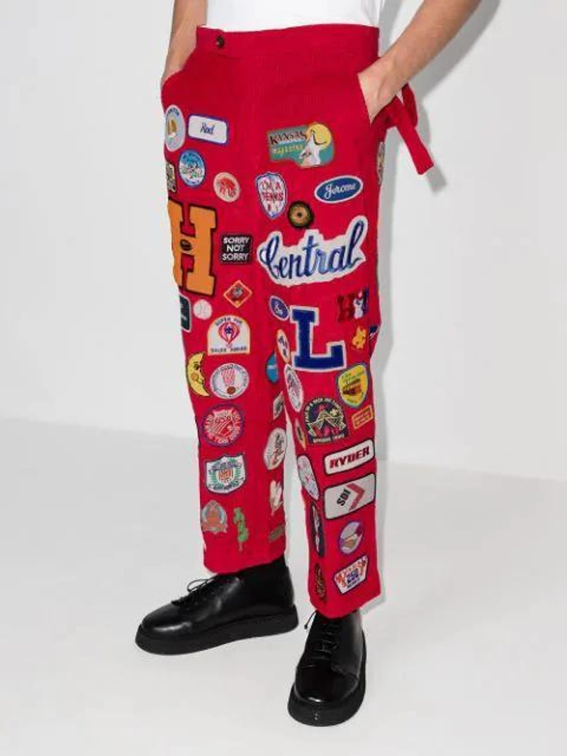 Farfetch's Post | Wearing: Bode Multi Patch Straight Leg Trousers In Red; Maison Margiela Distressed V-neck Cotton-knit Jumper In Blue; Boramy Viguier Grail-print Cotton-jersey T-shirt In White