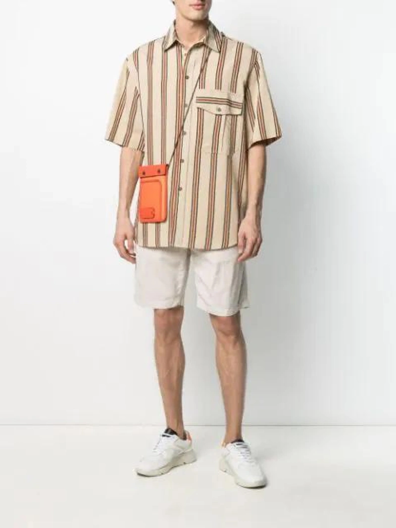 Farfetch's Post | Wearing: Song For The Mute Stripe Print Oversized Shirt In Neutrals; Aspesi Knee-length Shorts In Neutrals; Jw Anderson Pulley Clutch Bag In 433 Br Orng